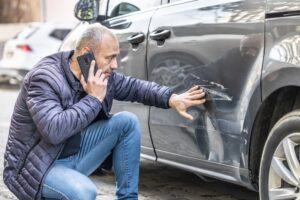 a man calls the insurance company or the police because someone backed into the side door of his car in the parking lot