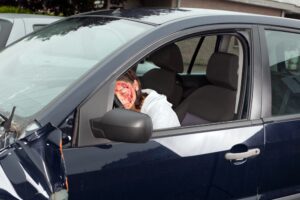young woman driver with bleeding face after car accident