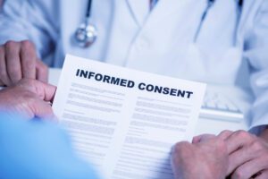 a senior caucasian man, at the doctors office, reading an informed consent document in front of a caucasian doctor man